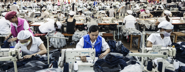 Eine Arbeiter steht an einer Nähmaschine in einer Textilfabrik.