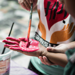 Eine Kinderhand wird mit Farbe bemalt.