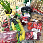 Voller Einkaufswagen mit verpacktem Obst, Gemüse und Pflanzen