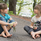 Zwei Mädchen sitzen sich gegenüber auf der Straße und sprechen miteinander.