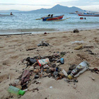 In Regionen, wo der Tourismus wichtig ist, müssen Strände oft vom angespülten Müll gereinigt werden. Vermüllter Strand und Sportboote in Indonesien