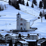 Eine Kirche oberhalb eines Bergdorfes im Winter.