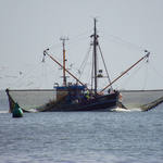 Fischerboot mit ausgebreiteten Netzen im Meer.