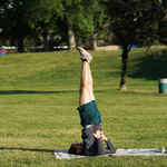 Mann macht Yoga-Figur auf grüner Wiese.