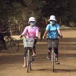 Zei Frauen mit Atemmasken auf Fahrrädern
