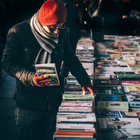 Ein Mann steht vor einem Tisch mit gebrauchten Büchern und schaut sich um.