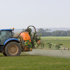 Traktor verteilt Insektenschutzmittel auf Feld.