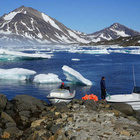 Wie in anderen Regionen der Welt geht auch auf Grönland das Eis der Gletscher durch den Klimawandel zurück. Gletscher und Festlandeis auf Grönland, vorne zwei Boote und Menschen
