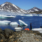 Gletscher und Festlandeis auf Grönland, vorne zwei Boote und Menschen