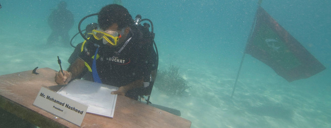 Taucher sitzt unter Wasser am Schreibtisch.