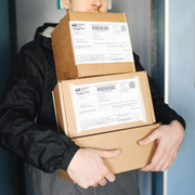 Häufig werden werden mehrere Pakete zusammen zugestellt. Ein Paketbote trägt drei Pakete.