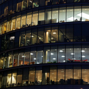 Ein Bürogebäude mit mehreren Fenstern bei Nacht, in denen das Licht brennt. 