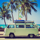 VW-Camper vor sonnigem Strand mit Palmen