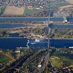 Das Bild zeigt den Grenzübergang zwischen Deutschland (Bildvordergrund) und Frankreich (Bildhintergrund) bei Breisach am Rhein. Im Vordergrund der begradigte Oberrhein mit einer Schleusenanlage. Der Rheinseitenkanal im Hintergrund wurde für die Schifffahrt angelegt.  