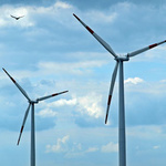 Zwei Windräder und ein Vogel der fliegt