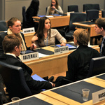 Jugendliche sitzen in einem Konferenzsaal und sprechen miteinander.