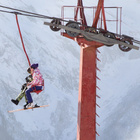 Der Wintersport ist für viele Orte in den Alpen ein wichtiger Wirtschaftsfaktor. Zahlreiche Urlaubsgäste freuen sich auf Skifahren und Snowboarden. Zwei Menschen sitzen in einem Sessellift, neben ihnen der Stützpfeiler der Liftanlage.