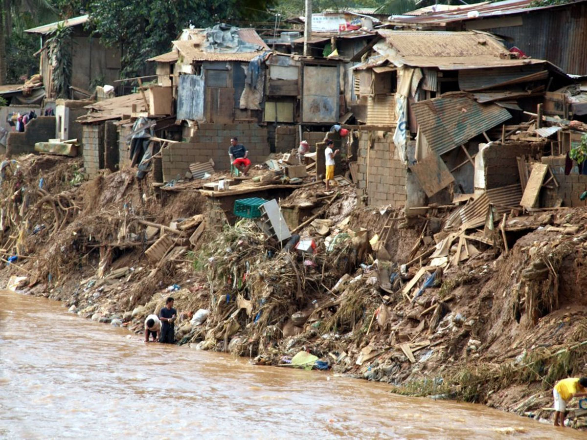 Ein brauner Wasserstrom schnellt durch einen zerstörten Slum