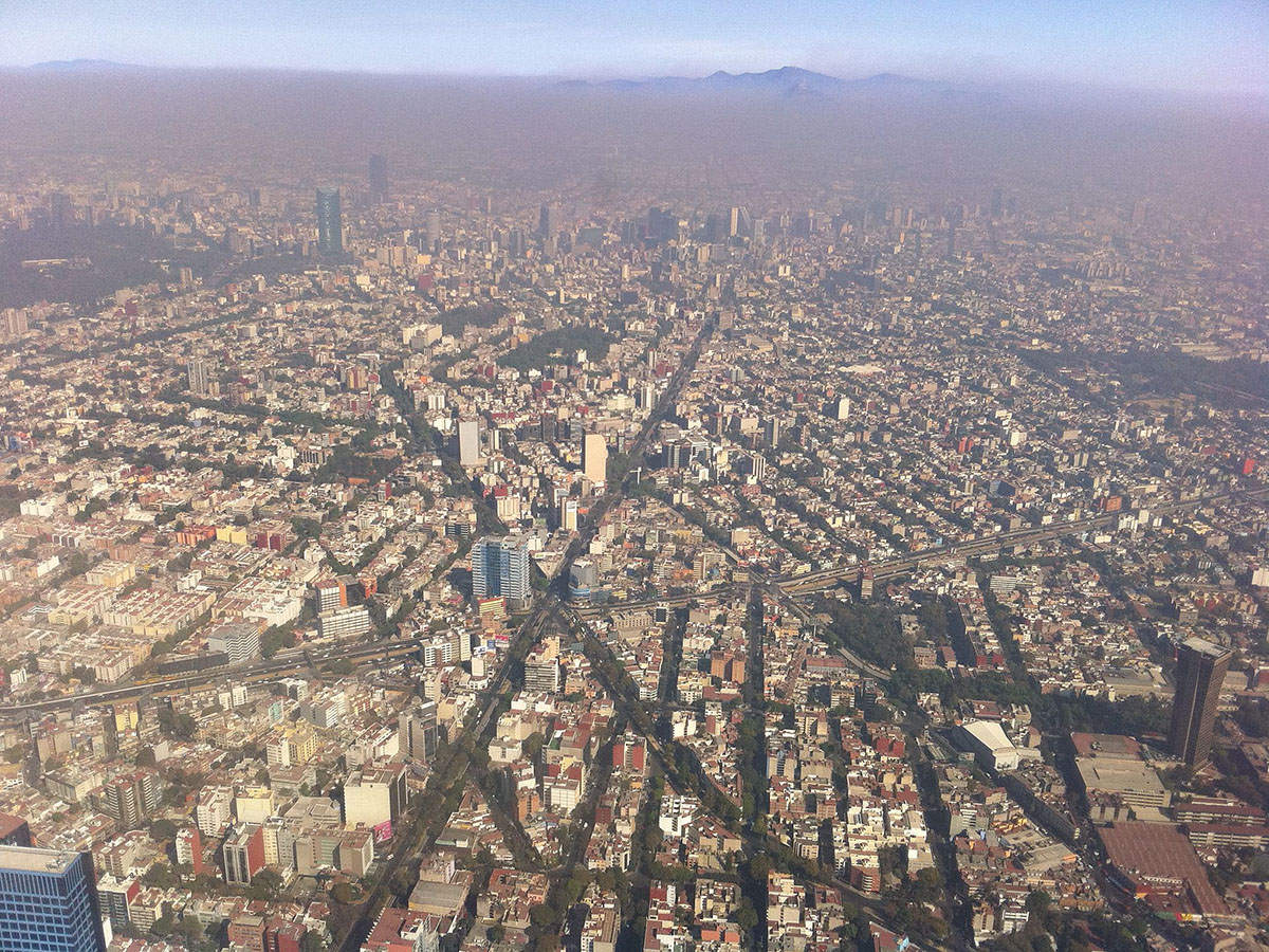 Luftaufnahme einer sich weit ausbreitenden Stadt unter einer Smogschicht