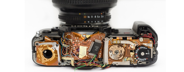 Aufnahme einer Spiegelreflexkamera, bei der die obere Abdeckung fehlt und das Gehäuse mit der inneren Technik zu sehen ist. 