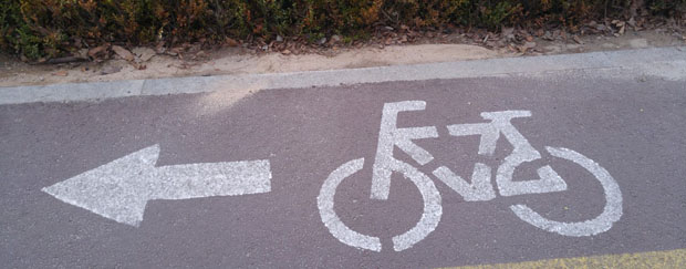 Ist der eigene Pkw ersetzbar durch Fahrrad, öffentliche Verkehrsmittel und Carsharing? Fahrradweg mit aufgedrucktem Fahrrad und Pfeil
