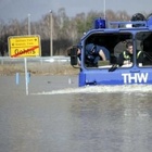 Der Klimawandel führt in manchen Ländern zu vermehrten Niederschlägen und Hochwasser - auch in Deutschland. Wagen des Technischen Hilfswerks im Hochwasser; daneben Ortsschild im Wasser