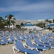 Liegestühle an einem Strand; im Hintergrund Hotels