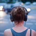 Um dem Stadtlärm zu entkommen, hören viele Menschen mit Kopfhörern Musik. Das Gehör kann jedoch auch durch laute Kopfhörer geschädigt werden. Frau mit Kopfhörer
