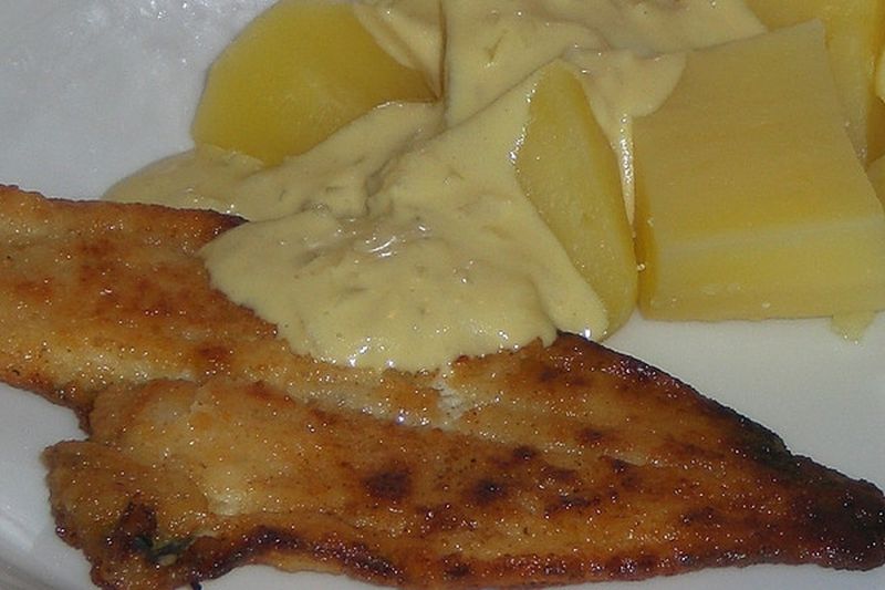 Backfisch mit Kartoffeln und Soße auf einem weißen Teller