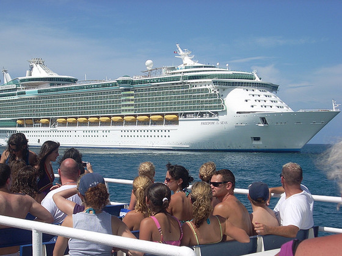 Urlauber auf dem Sonnendeck eines Schiffes beobachten ein Kreuzfahrtschiff.