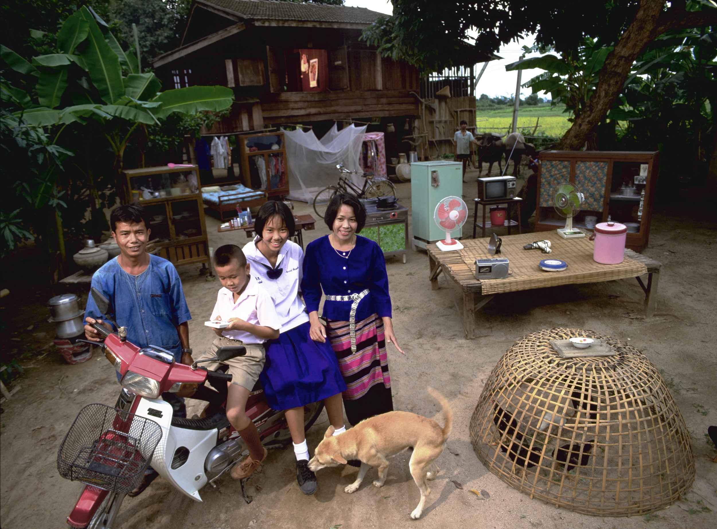 Thailändische Familie mit ihren wenigen Habseligkeiten vor ihrem Haus.