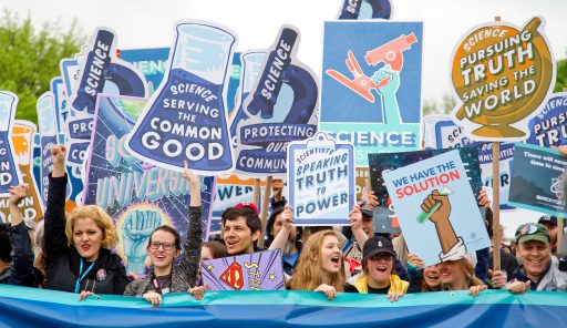Gruppe von Menschen mit Bannern und Schilder "Science serving the Common Good"