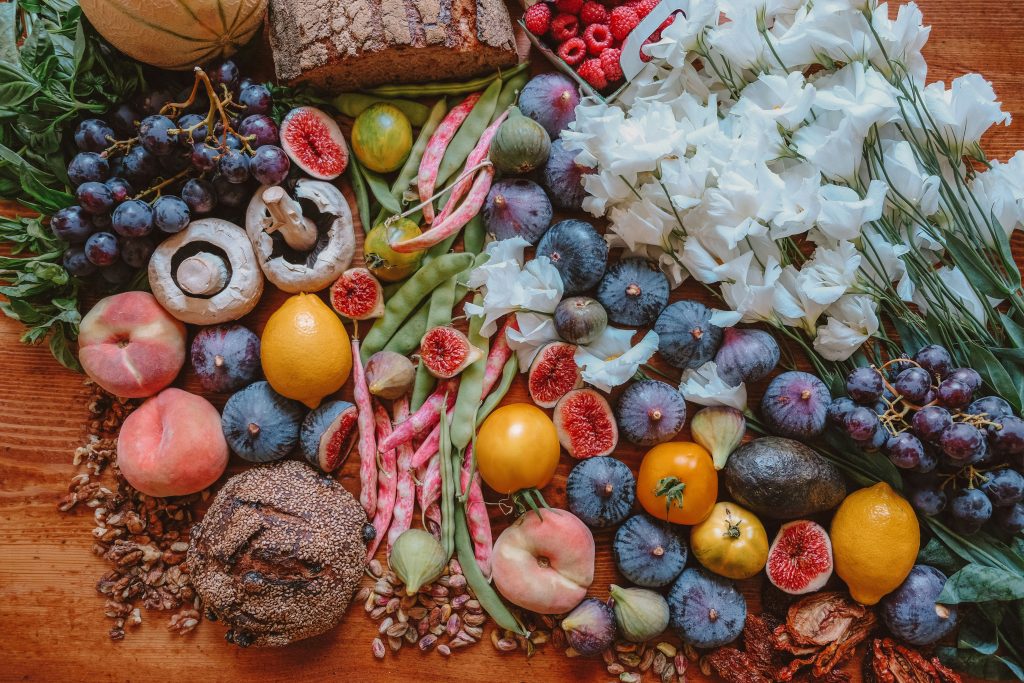 Früchte, Brot und Blumen liegen auf einem Holztisch