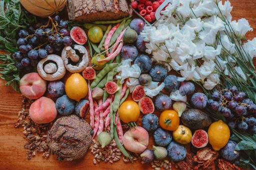 Früchte, Brot und Blumen liegen auf einem Holztisch