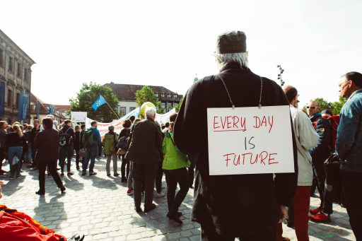 Mann steht mit Schild "Everday is Future" am Rücken in einer Demonstration
