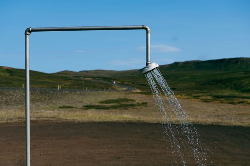 Wasser strömt aus einem Rohr mit Duschkopf auf einem Feld