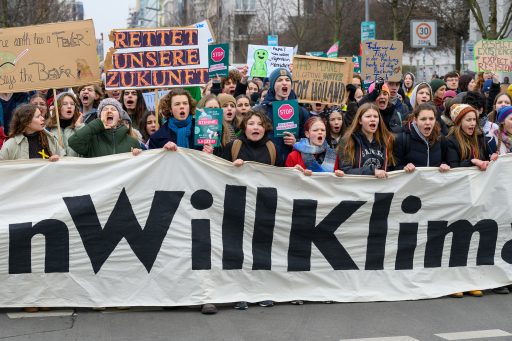 Demonstranten halten ein großes Banner und Schilder mit Aufschriften wie 'Rettet unsere Zukunft' bei einer Klimaprotestaktion