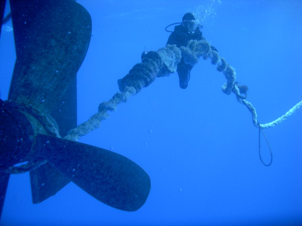 Taucher befreit Schiffsschraube, die in dickes Seil verheddert ist, unter Wasser