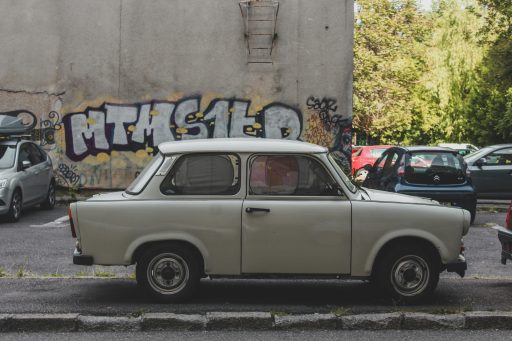 Beiger Trabant Oldtimer-Pkw steht vor einer Wand mit Graffiti in einem Parkplatz