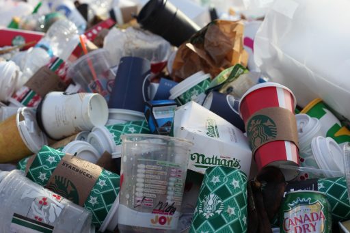 Viele weggeworfene Einwegbecher von Starbucks und Nathan's sowie Plastikbecher und Papierverpackungen in einer Mülltonne