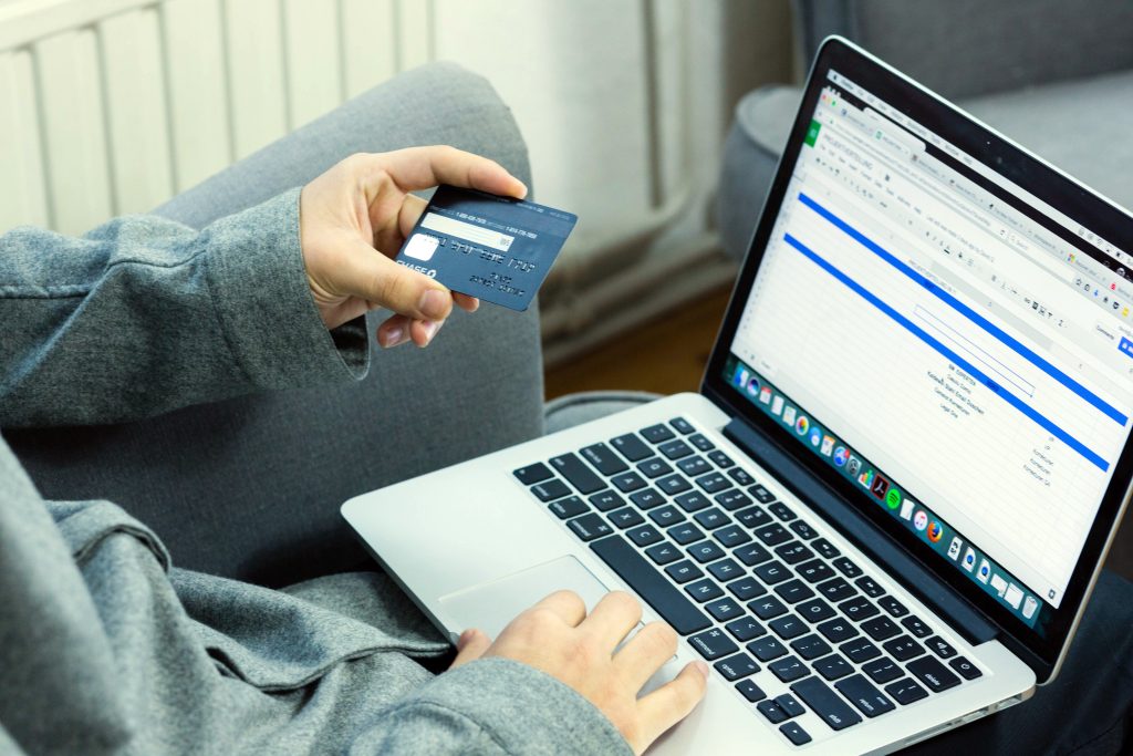 Person hält Kreditkarte und benutzt Laptop für Online-Einkauf