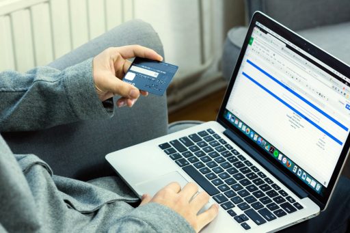 Person hält Kreditkarte und benutzt Laptop für Online-Einkauf