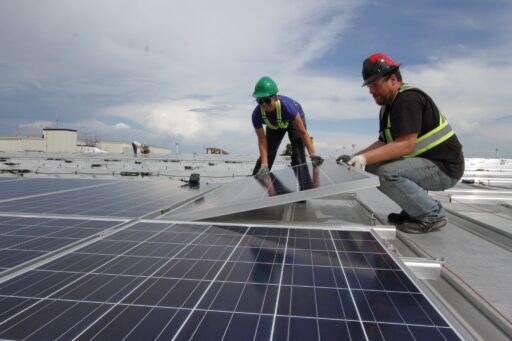 Zwei Installateure montieren eine Solarplatte.