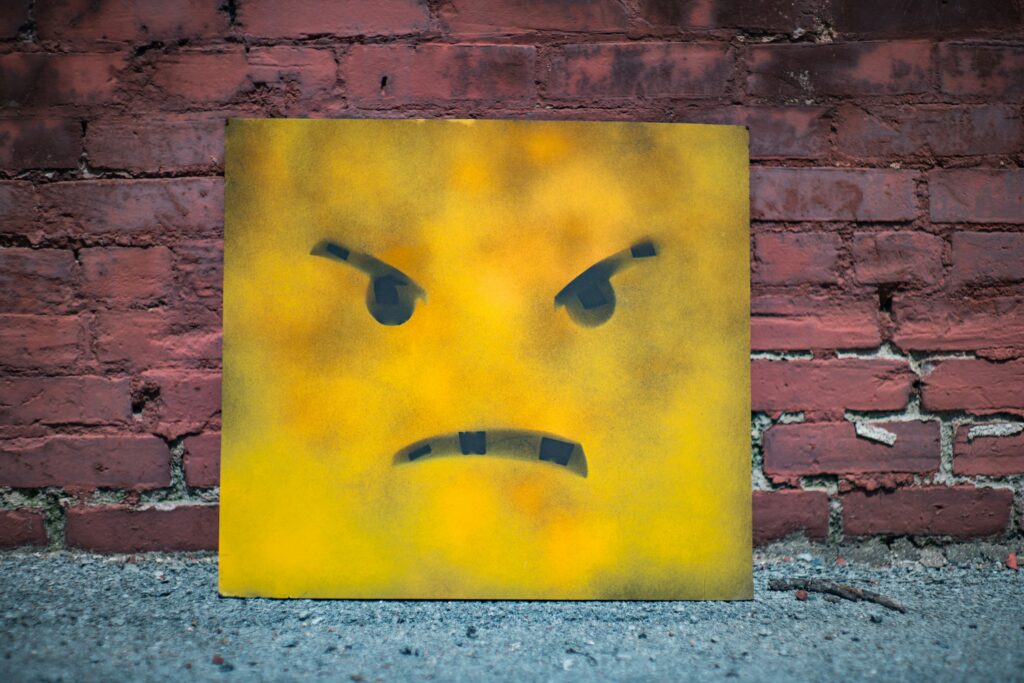 Ein Smiley-Gesicht vor einer Ziegelwand mit einem grimmigen Ausdruck.
