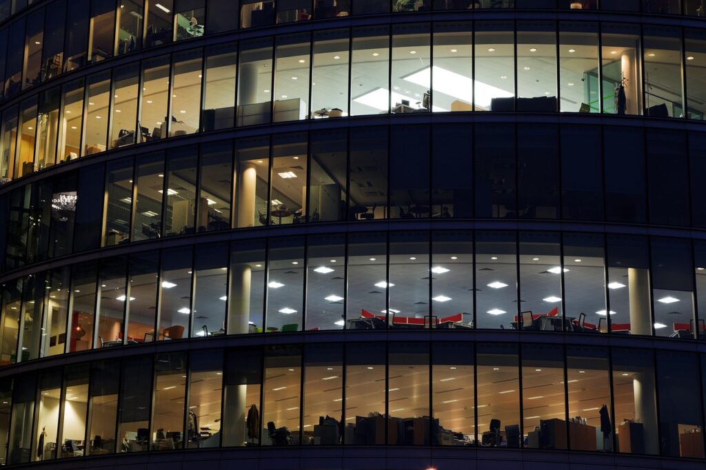 Ein mordernes Glasgebäude bei Nacht. Die Fenster sind hell erleuchtet.