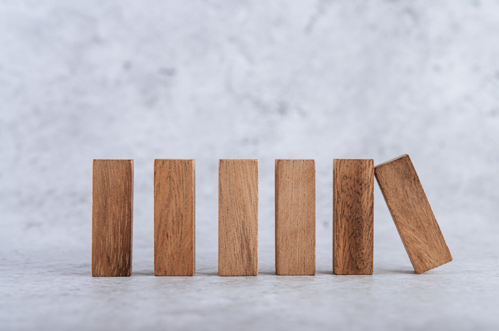 Ein hölzerner Domino Steine kippt auf weitere Steine.