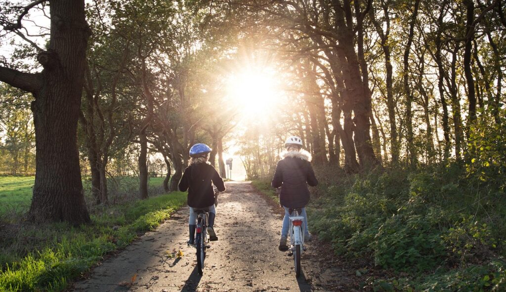Zwei Mädchen fahren Rad auf einem Waldweg mit Helm