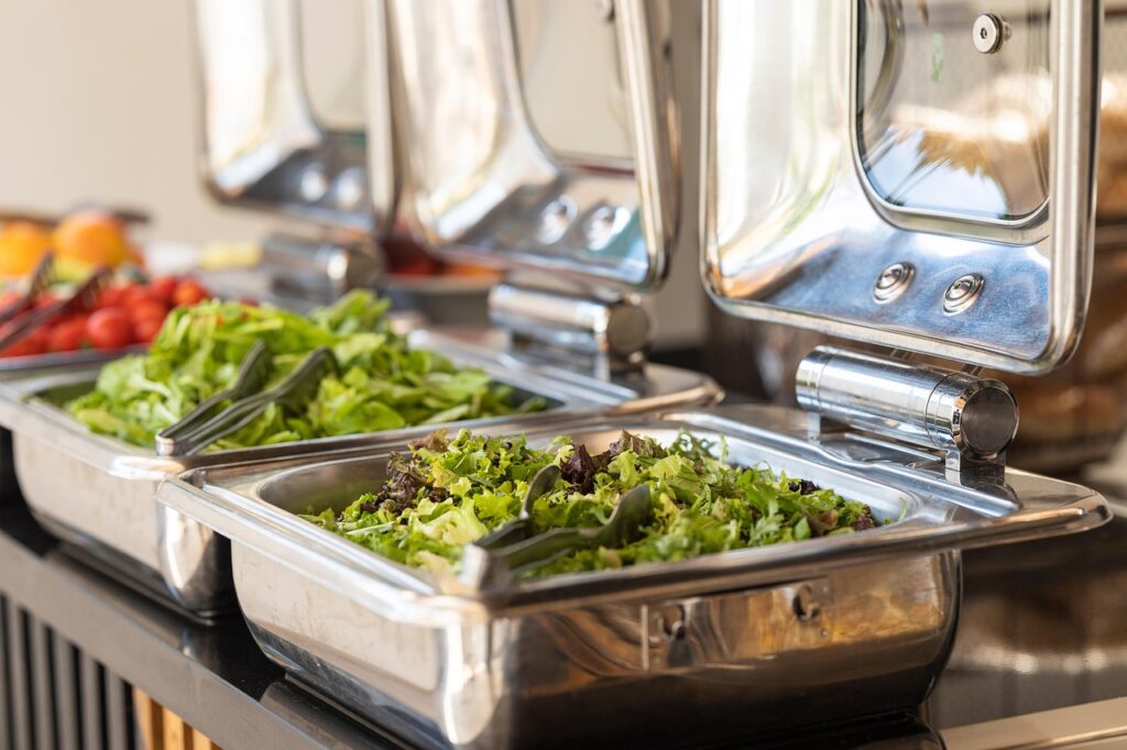 Buffet mit großen Metallformen mit Blattsalat.