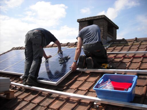 Zwei Männer montieren Solarpanel auf einem Dach.