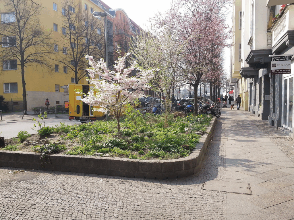 Großes Beet mit Bäumen und anderen Pflanzen im zwischen Gehweg und Straße in Berlin-Kreuzberg.